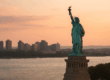 Sunset view of the Statue of Liberty with the New Jersey skyline across the Hudson River.
